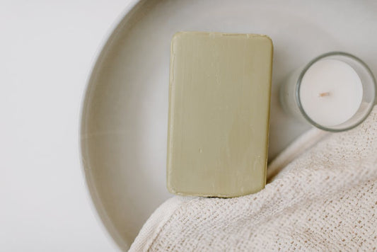 Minimalist image of a soap bar and candle on a tray, highlighting relaxation and self-care.