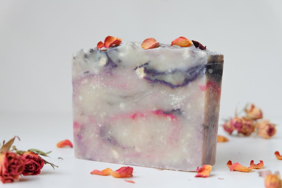 Artisan soap bar featuring dried rose petals on a white background.