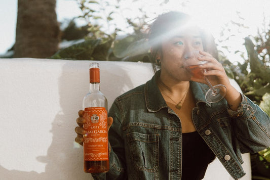 A woman savoring a glass of rosé wine in sunny outdoor setting, Portugal.